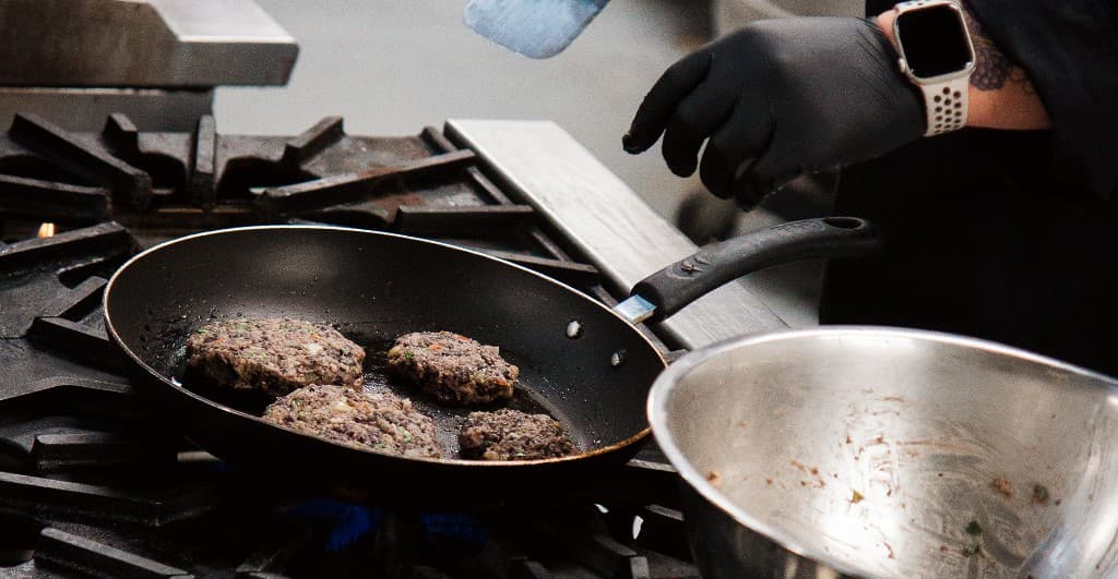 Chef searing patties on the range in the Squatch Meals kitchen
